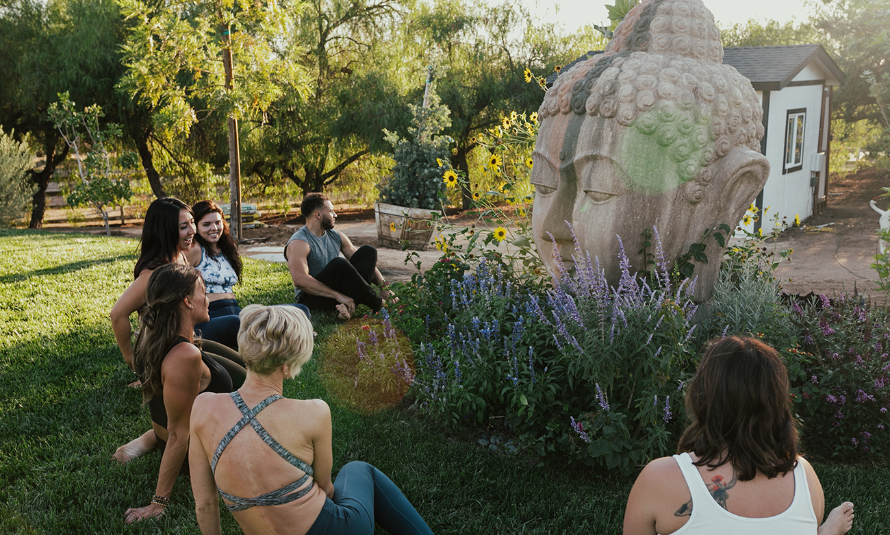 Yoga students sitting by Buddah